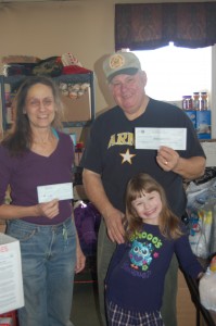 Mary James, from HAYS Cleaning, Inc., presents checks to Jim Kruse. The funds will be used to purchase goods and ship boxes to troops overseas. Also pictured, Jim's granddaughter.
